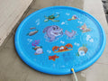 Blue PVC children's water spray pool mat with marine animal designs laid out on grass