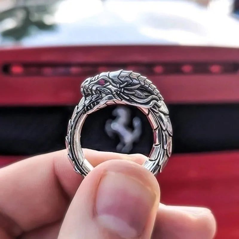 Vintage dragon male ring in ancient silver metal on a plain background.