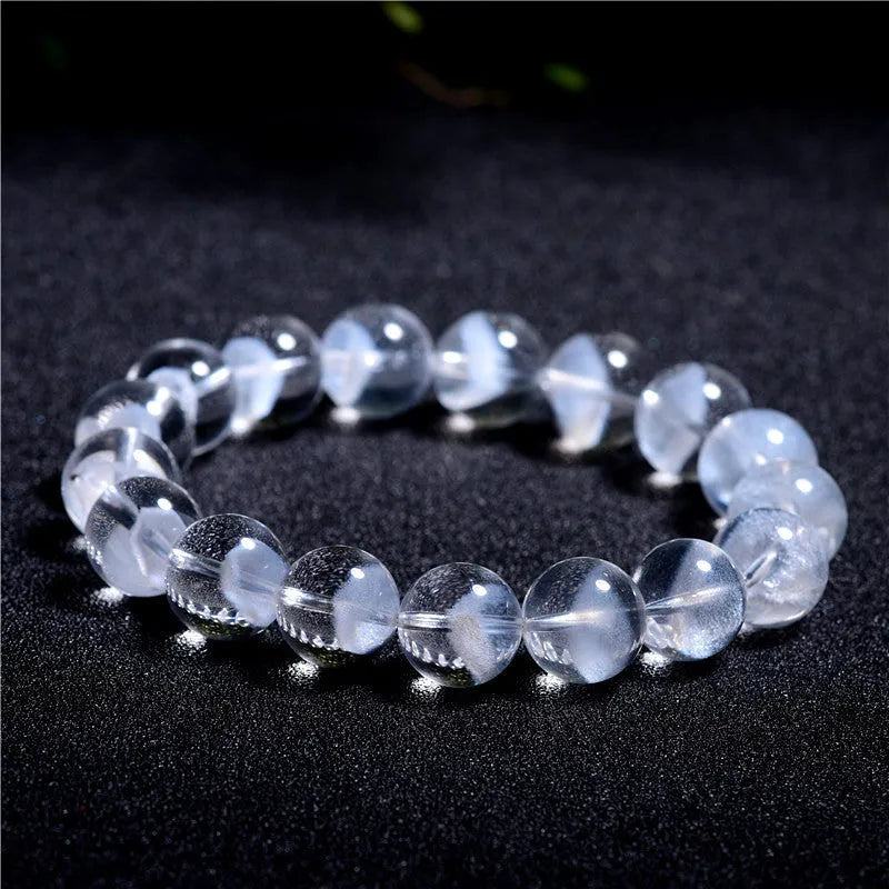 Women's white crystal bracelet with ghost pyramid beads and a ruyi charm, shown on a wrist.