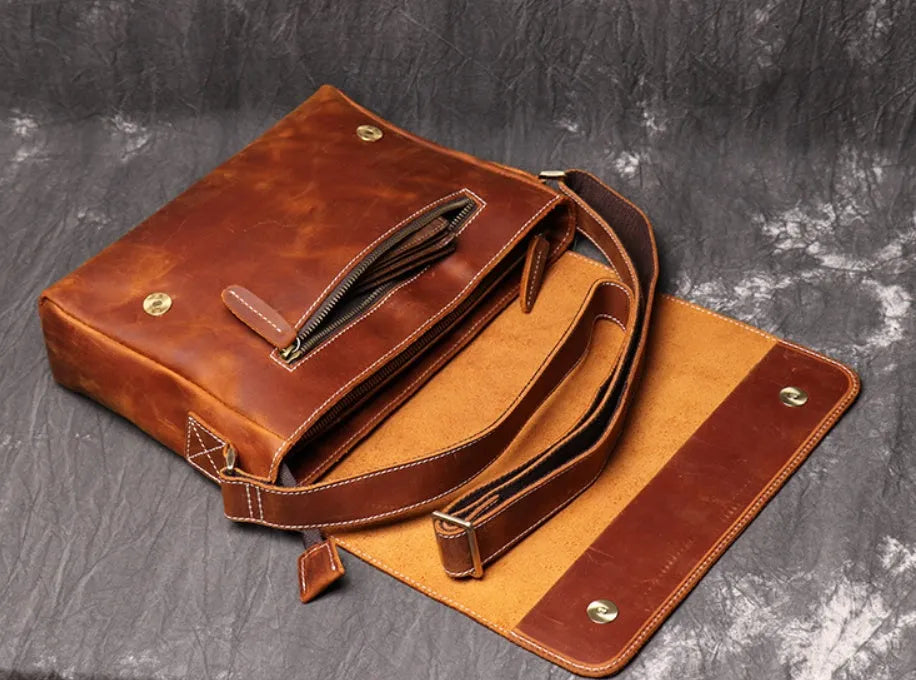 Vintage brown men's leather messenger bag showing interior compartments and adjustable shoulder strap