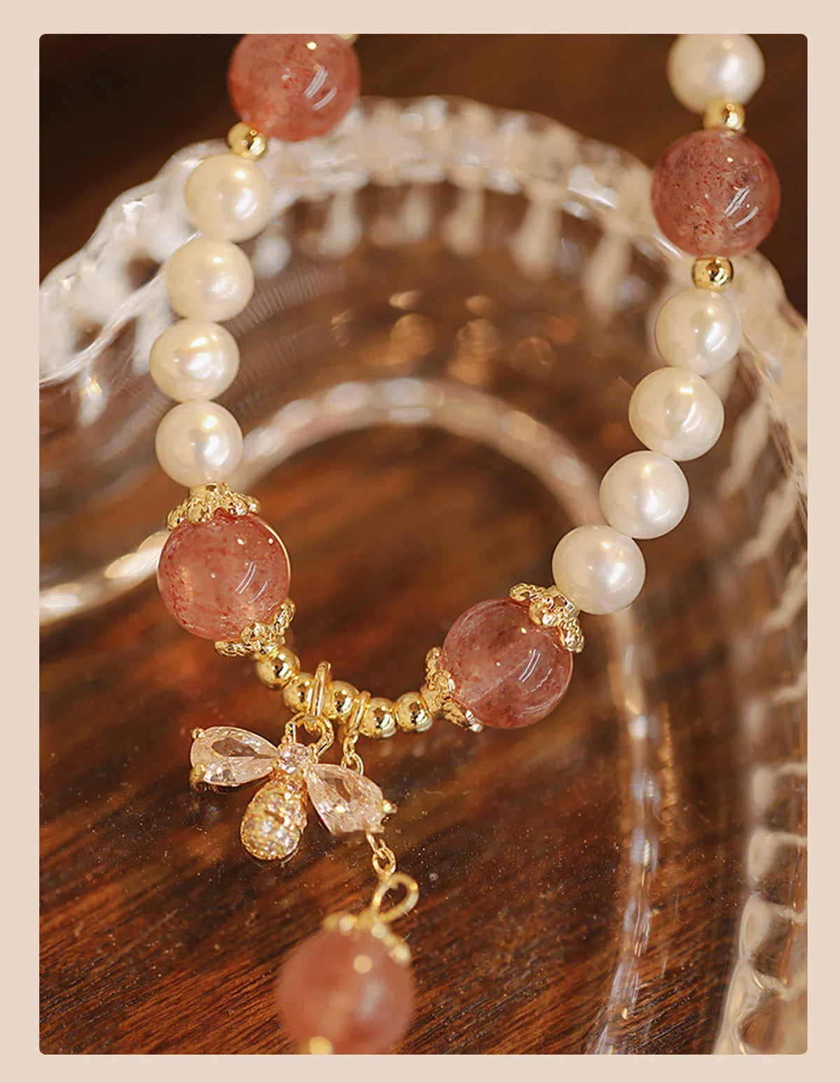 Close-up of a women's hand-strung strawberry quartz crystal bracelet with a decorative bow.