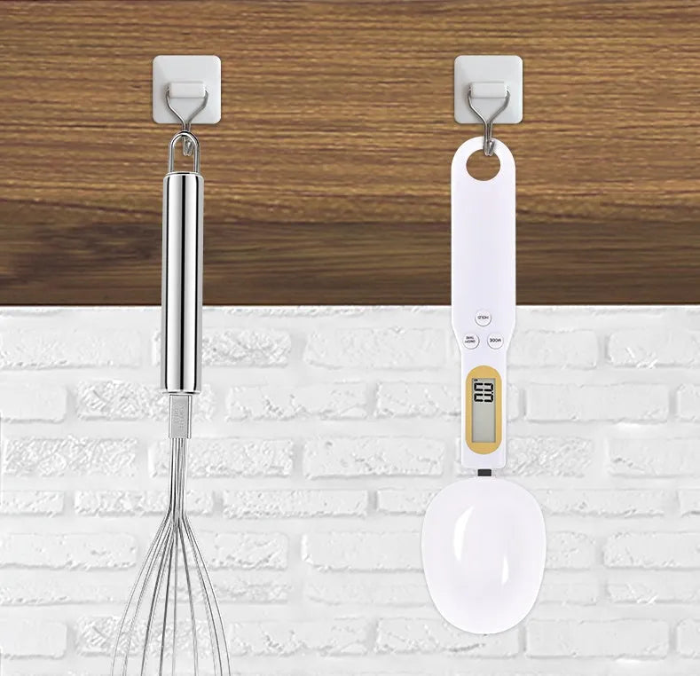 Black electronic measuring spoon scale with digital display on handle and integrated spoon bowl.