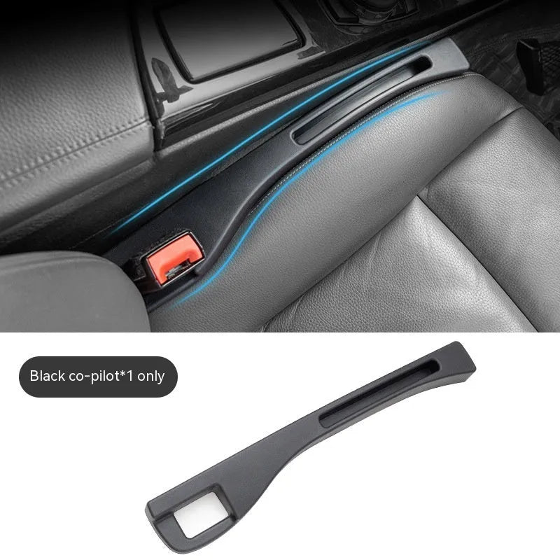 Black plastic car seat gap storage box with handle inserted between car seats.