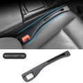 Black plastic car seat gap storage box with handle inserted between car seats.