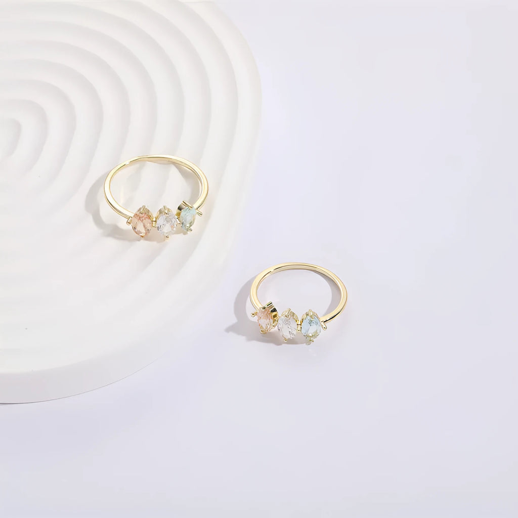 Gold colour geometric triangle ring with horse eye design and tricolour zircon stones on a white background