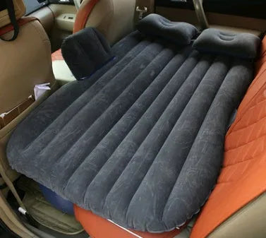 Inflatable car bed with flocked surface folded beside storage bag and two pillows