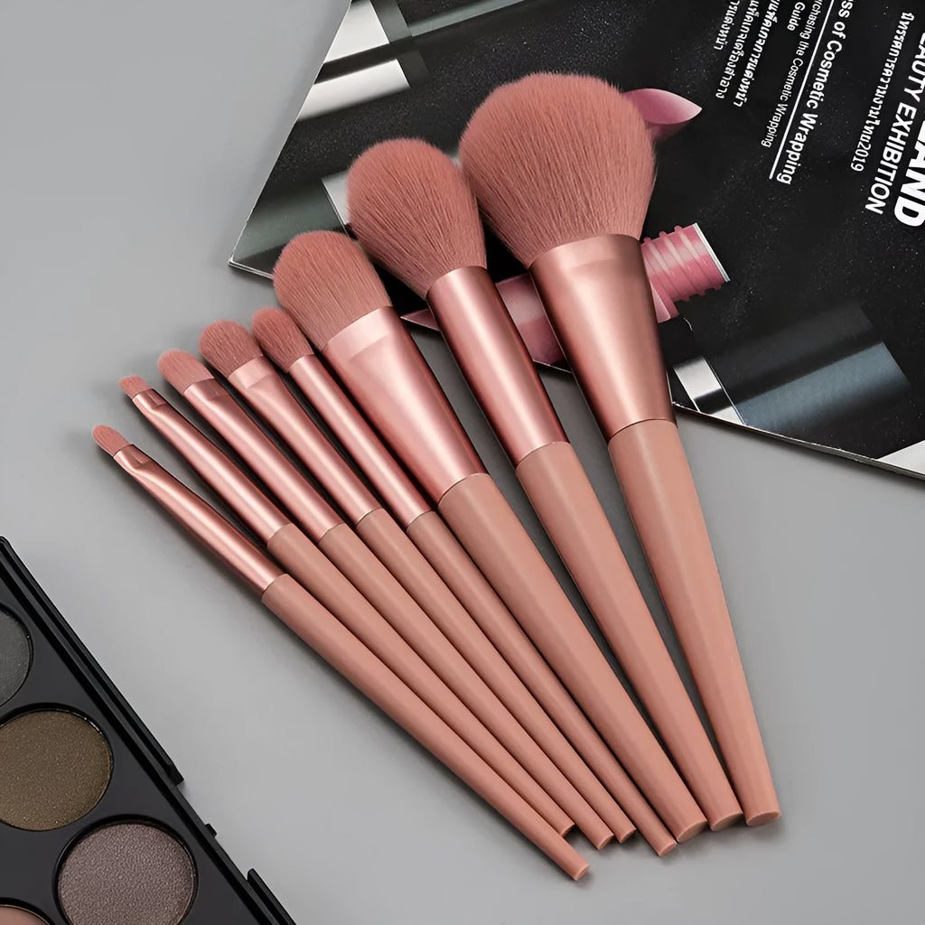 Pink 8-piece makeup brush set with man-made fibre bristles and plastic handles on a light background.