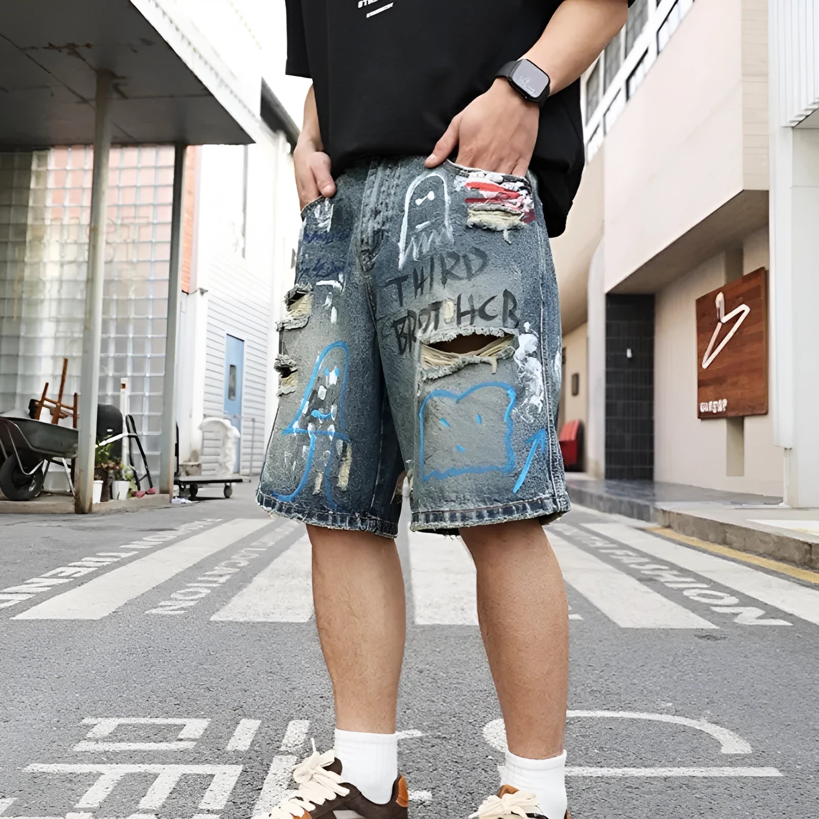 Blue ripped men's denim shorts with graffiti design, showing straight leg and zipper fly.