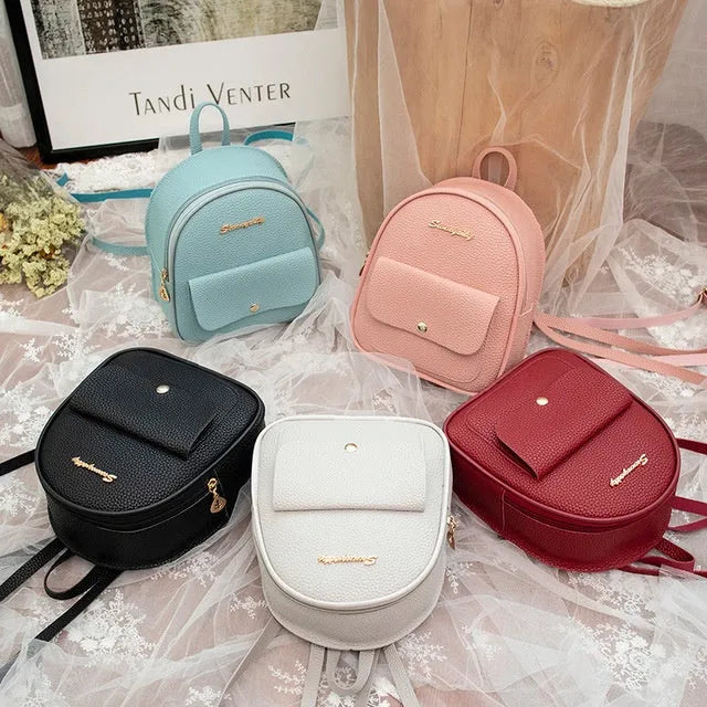 Small black women's backpack shoulder bag with zipper closure shown next to a mobile phone for scale