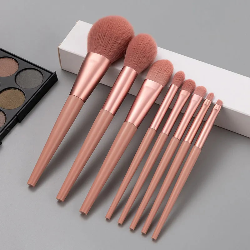 Pink 8-piece makeup brush set with man-made fibre bristles and plastic handles on a light background.