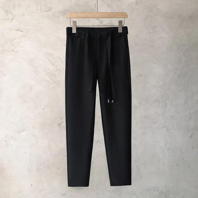 Boy wearing slim straight wool trousers in a neutral colour, showing tapered leg and straight hem.