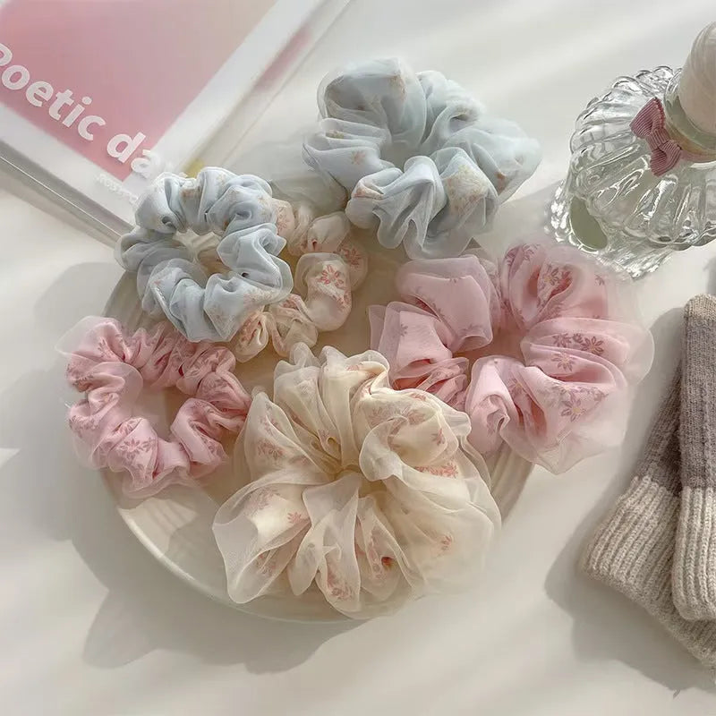 Mesh sense polyester large intestine hair band in milky white, pink, and light blue on a plain background