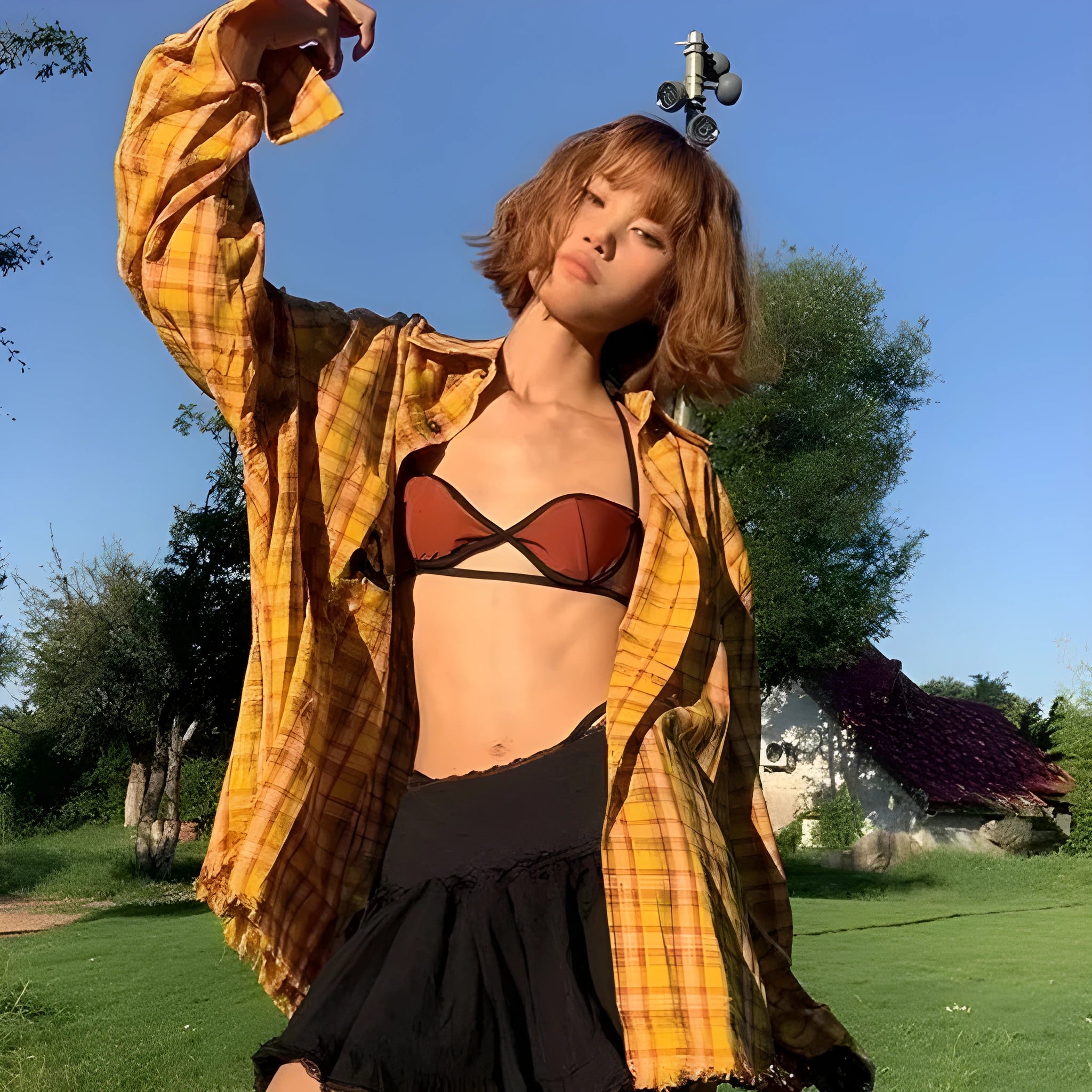 A man or woman wearing a loose-fitting yellow plaid cardigan-style shirt.