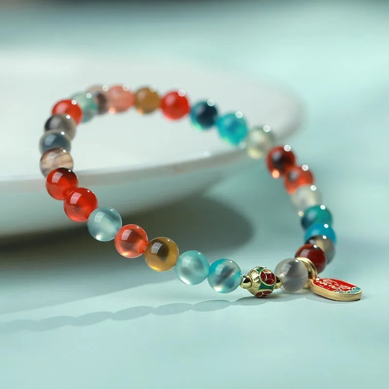 Natural agate and coloured glaze snake bracelet with copper coin charms on a white background.
