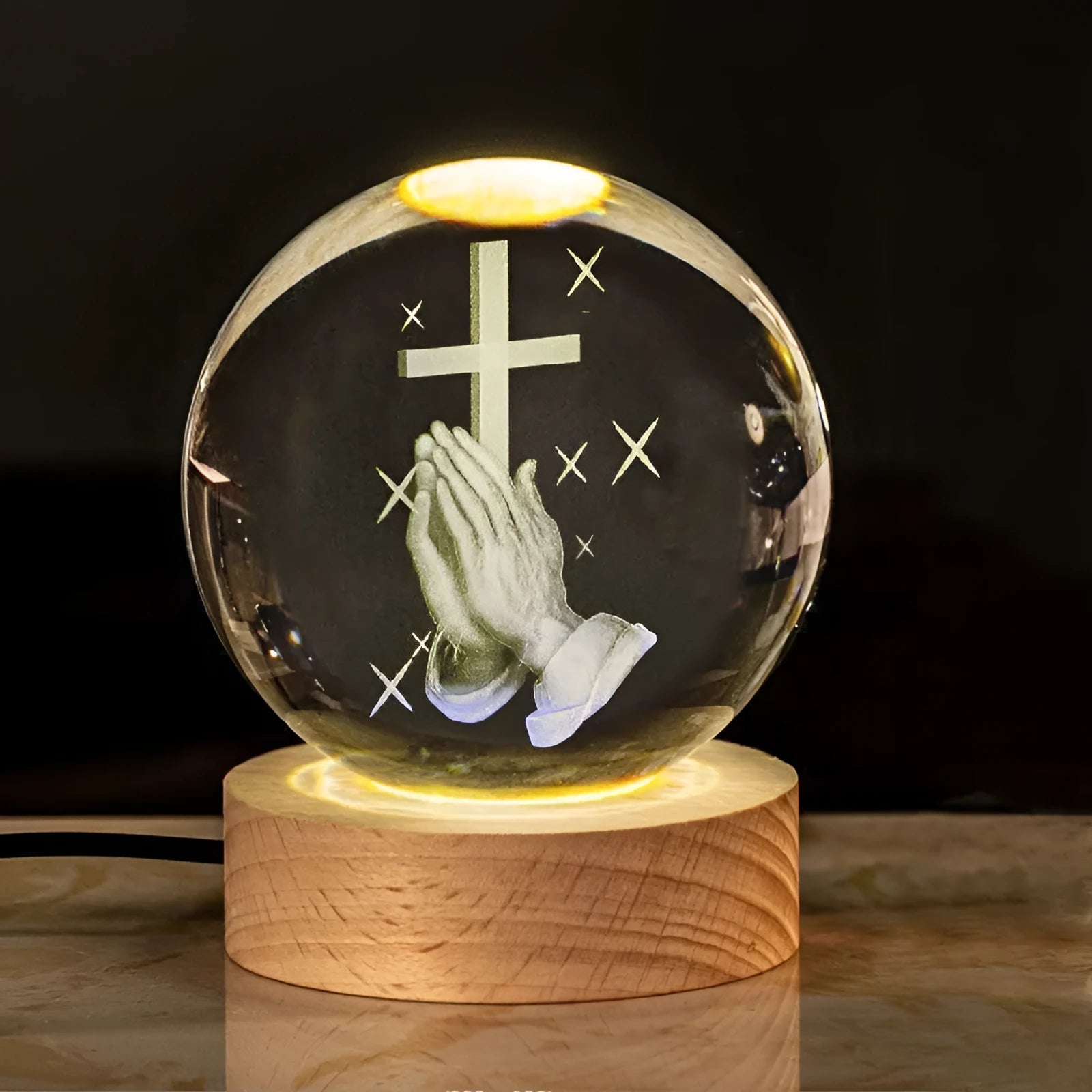 White crystal ball ornament on wooden base with religious symbols and warm light illumination