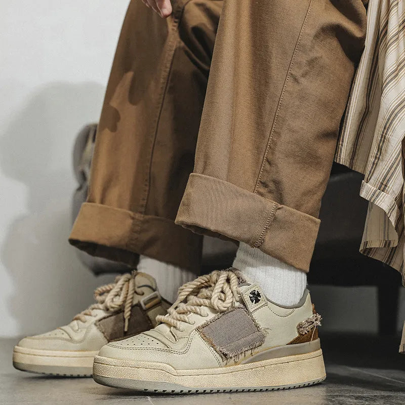 Beige low-top skateboard shoes with vintage patch detail and round toe on a rubber sole.