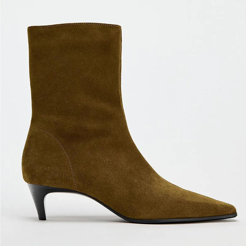 Brown square toe ankle boots with a side zipper and pointed stiletto heel on a wooden floor.