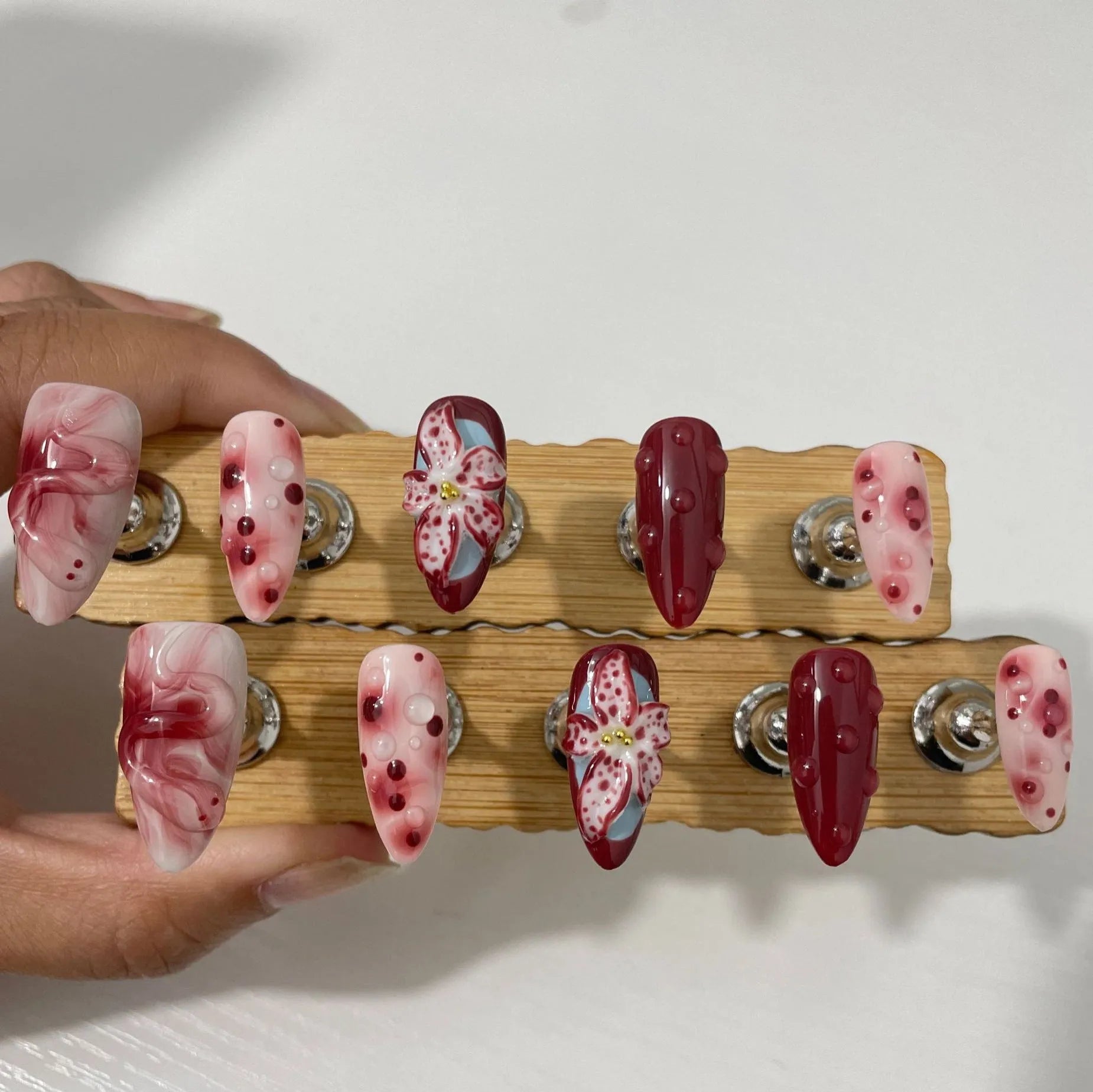 Hand-painted three-dimensional carved almond artificial nail extensions showing rose and tulip patterns