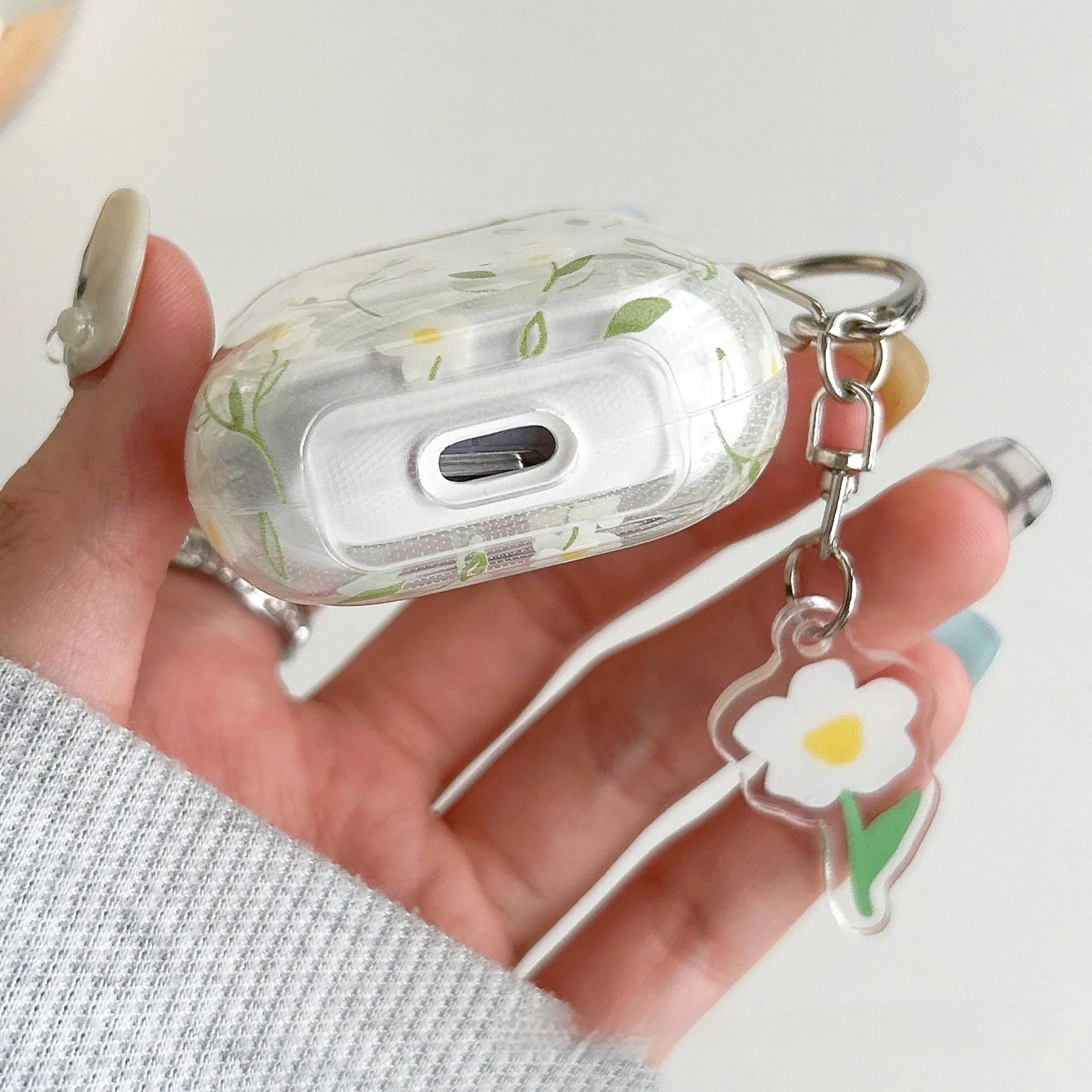 Transparent white floral TPU protective case for Apple AirPods headphones on a table.