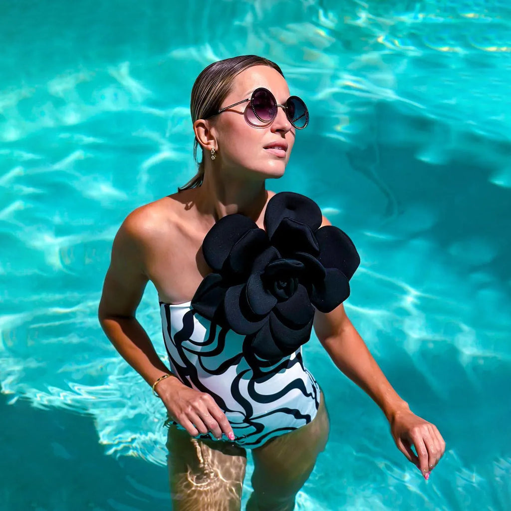 Women's one-piece swimsuit with three-dimensional floral design on black fabric.