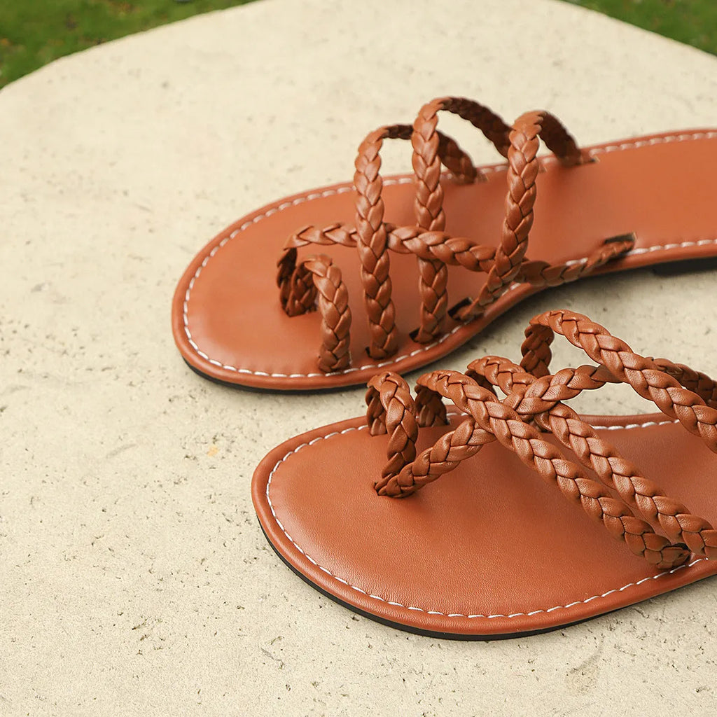 Women's white woven clip-toe flat sandals on a rubber sole, shown from a side angle.
