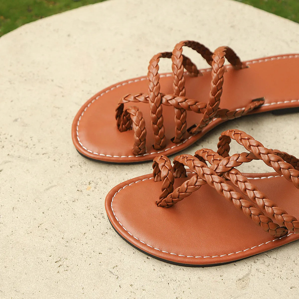 Women's white woven clip-toe flat sandals on a rubber sole, shown from a side angle.