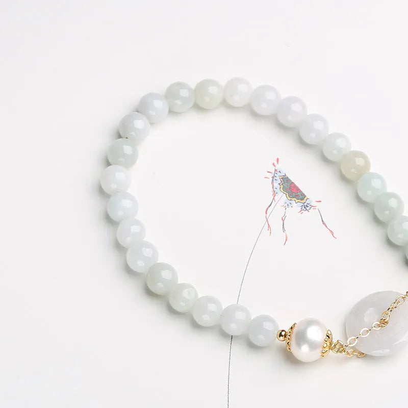 Natural green jade and pearl bracelet with peace buckle closure on wrist