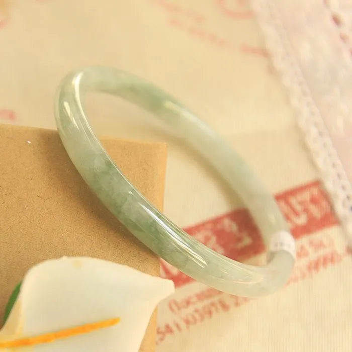 Green jade waxy stone geometric bracelet with Chinese style design on a wrist.