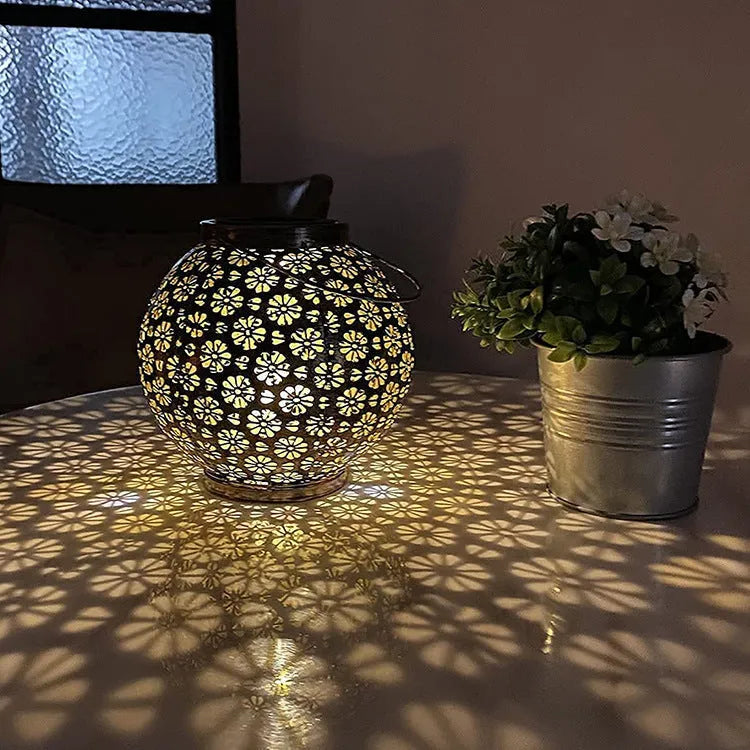 Solar wrought iron hollow flower projection lamp with warm white LED light and shadow pattern on grass