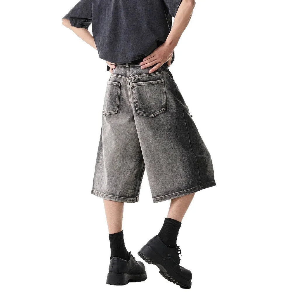 Grey distressed denim shorts with a loose cropped fit and hole details on a mannequin.