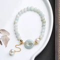 Natural green jade and pearl bracelet with peace buckle closure on wrist