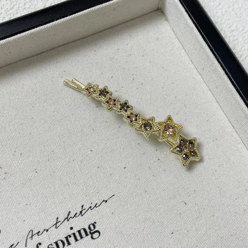Gold electroplated rhinestone barrettes with side clip design featuring star and letter charms