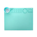 Light blue silicone painting mat with two round mixing bowls, placed on a wooden table with paintbrushes.