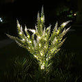 74cm tall pink lavender-shaped solar garden light with green stem, placed in a garden bed.