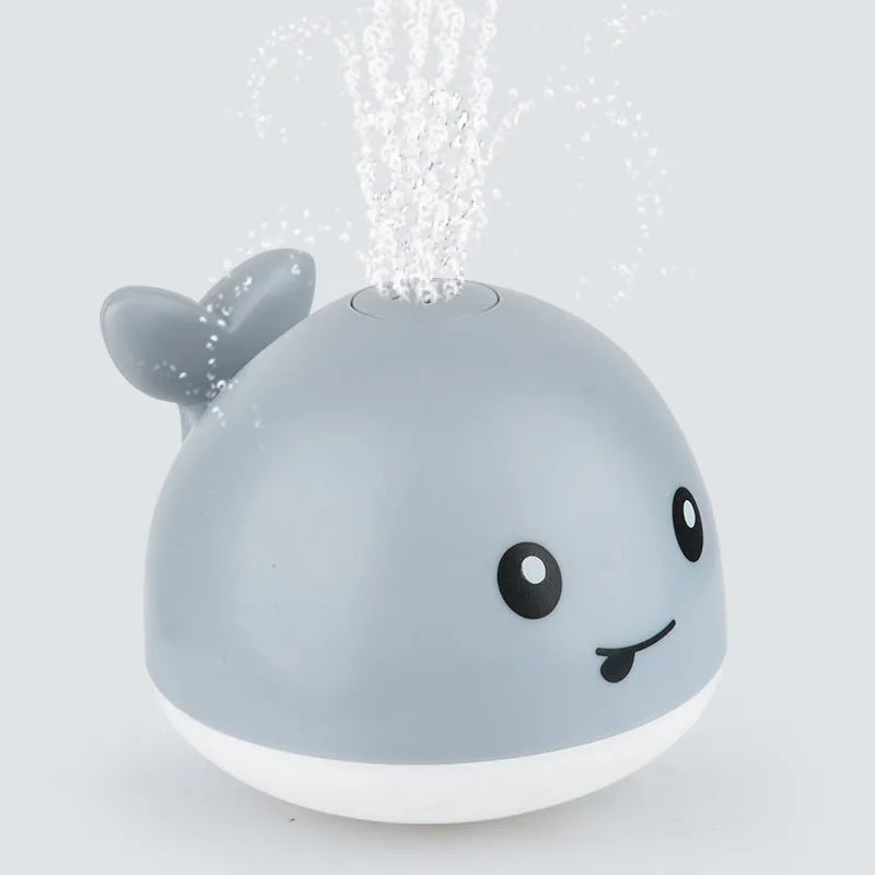 White and blue whale bath toy spraying water with LED lights illuminated