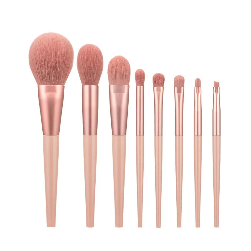 Pink 8-piece makeup brush set with man-made fibre bristles and plastic handles on a light background.