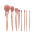 Pink 8-piece makeup brush set with man-made fibre bristles and plastic handles on a light background.