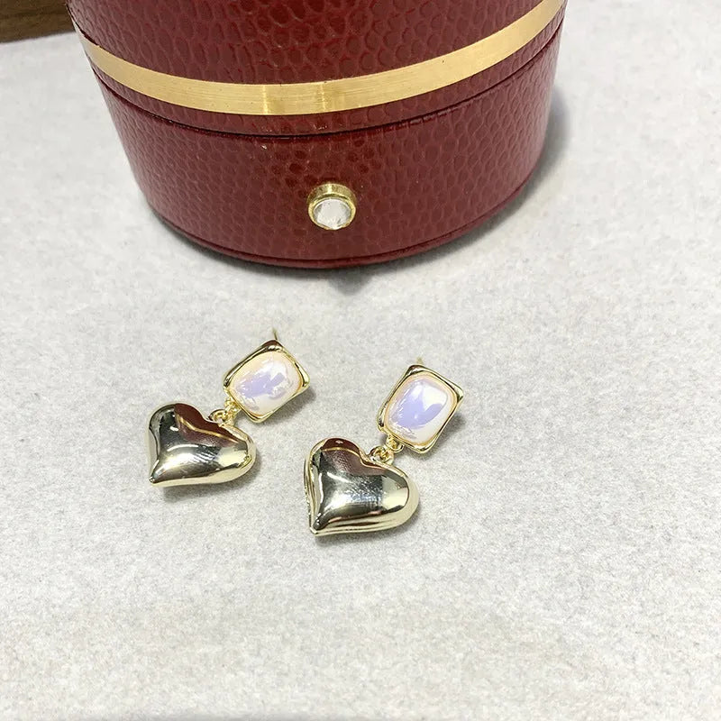 Small gold heart earrings with metal construction and post backing