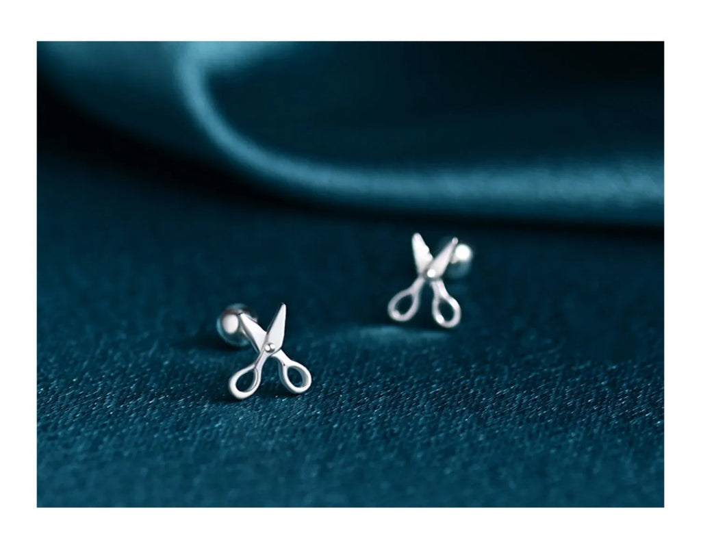 A pair of pure silver screw style ear nails with a miniature scissors design