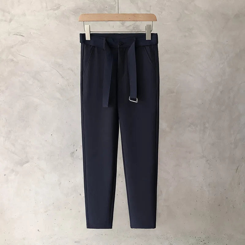 Boy wearing slim straight wool trousers in a neutral colour, showing tapered leg and straight hem.