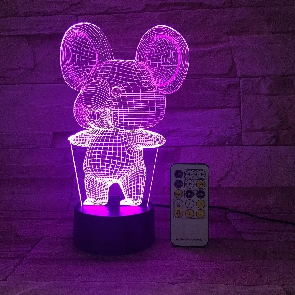 Black koala night light with colourful LED glow on a small table, showing remote control.
