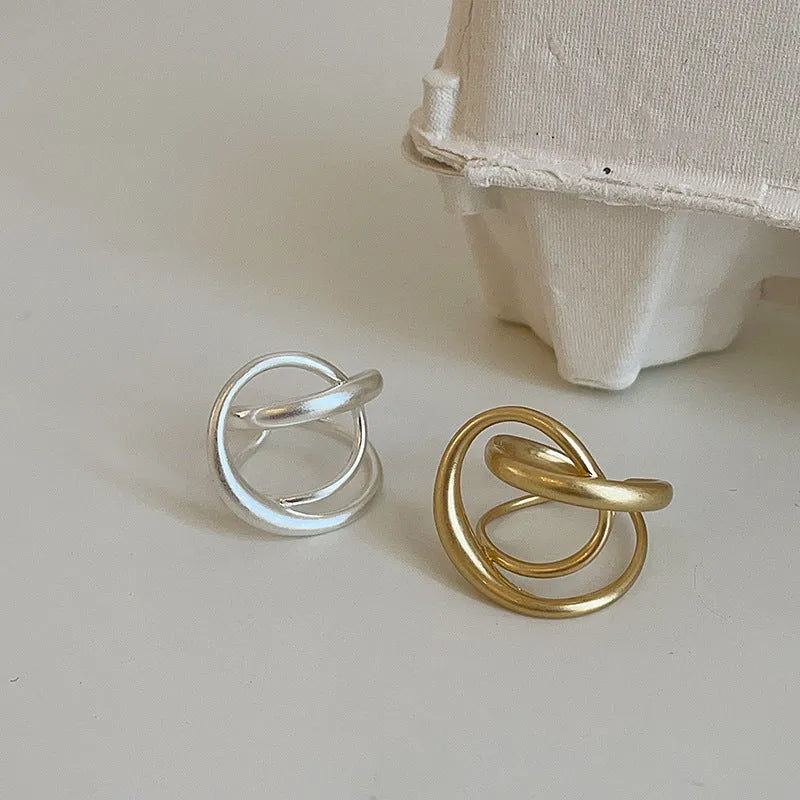 Geometric open ring for women with 3D interlaced matte metal design in gold and silver colour options.