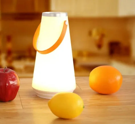 White rechargeable LED bedside lantern with USB cable on a table.