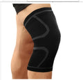 Close-up of a black double corrugated stretch knee pad for sports on a gym floor.