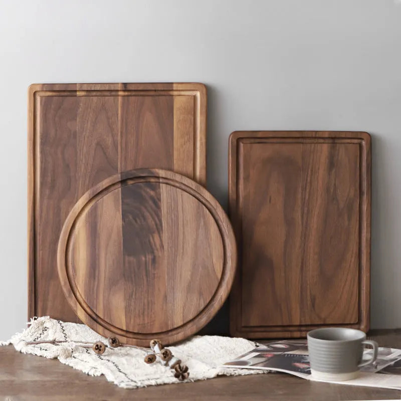 Black walnut wood cutting board with sauce groove and carved side handle on kitchen counter