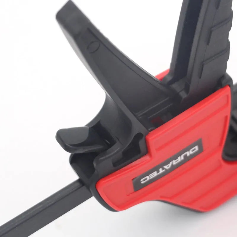 Black plastic woodworking clamp with rubber grip showing quick adjustment key and clamping mechanism