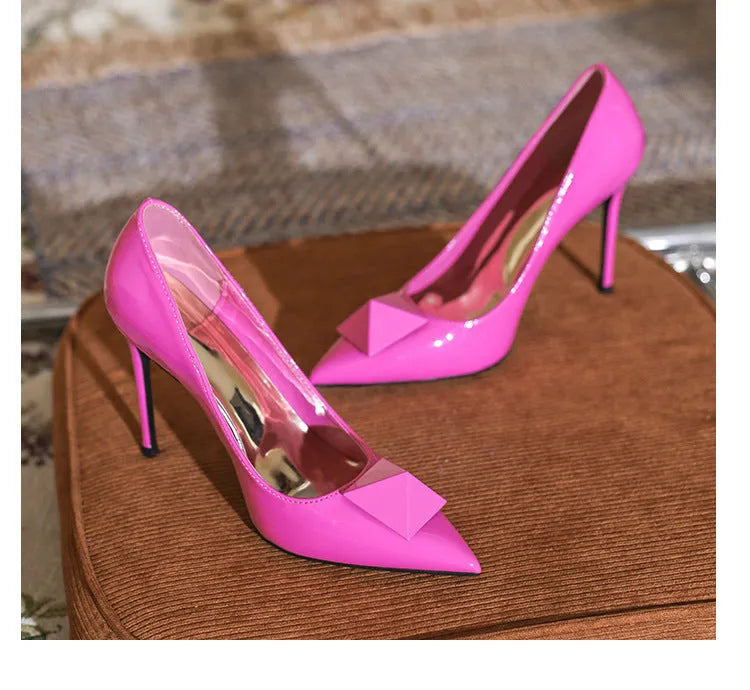Pink pointed toe stiletto high heels with rivet detail and a buckle on the patent leather upper.