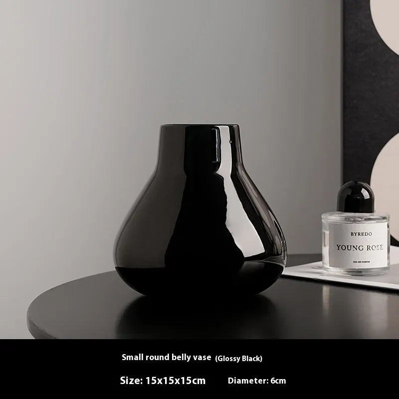 Black ceramic vase with round belly shape and two white flower ornaments arranged decoratively