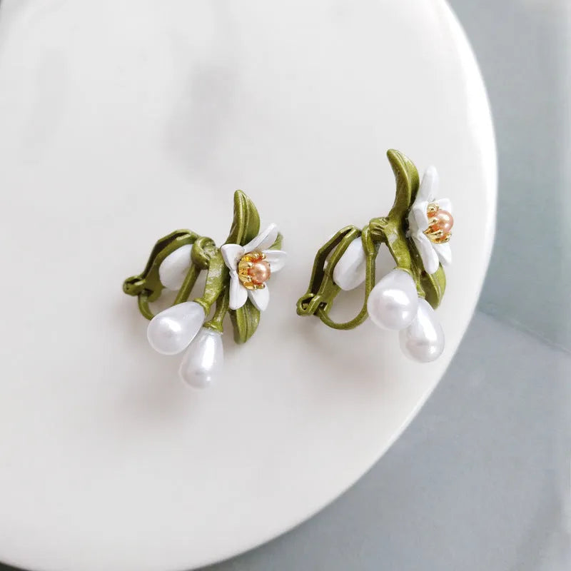 Women's alloy flower earrings with needle camellia design in sterling silver colour, shown as clip-on and ear stud styles