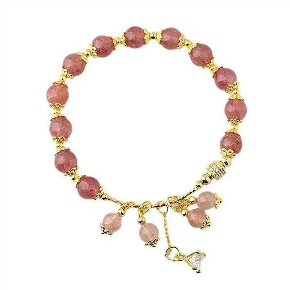 Close-up of a women's pink strawberry quartz heart bracelet with pearl details on a wrist.